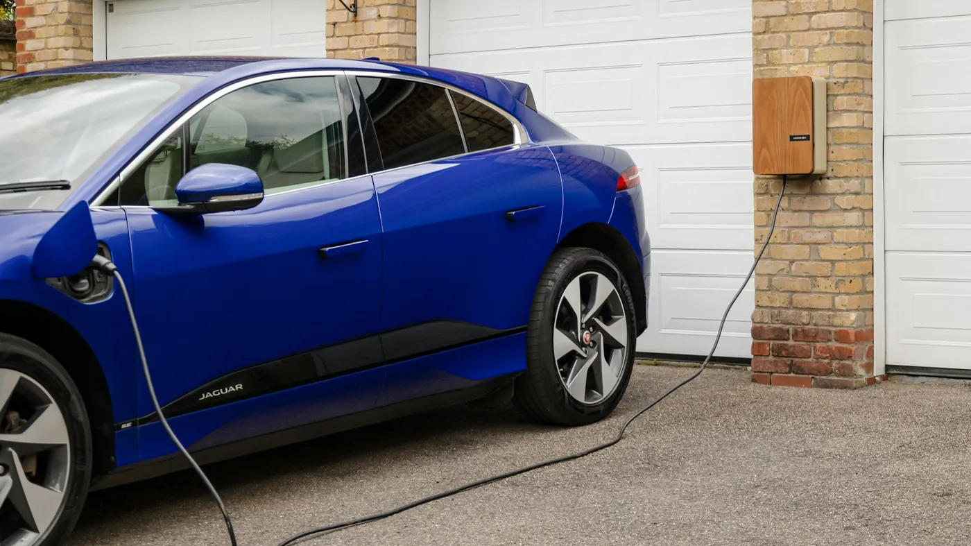 Blue electric car plugged into a Level 2 home charger inside a residential garage